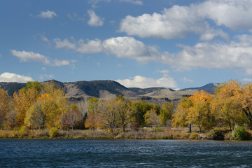 Autumn landscape of lake looking from Wheat Ridge Colorado toward Rocky Mountain foothills and mesa of Golden Colorado