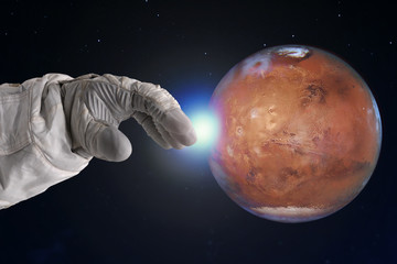 The development of Mars, concept. Hand of astronaut reaches out to Mars. Elements of this image...