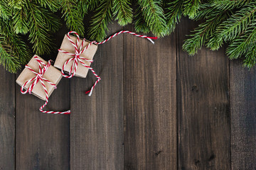 Christmas fir tree branches with gift box on dark rustic wooden background with copy space for text