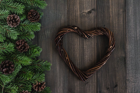 Christmas Fir Tree Branches With Pine And Heart Shaped Wreaths On Dark Rustic Wooden Background With Copy Space For Text