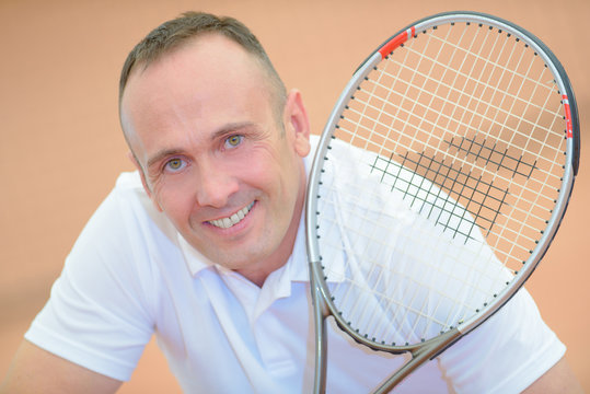 Portrait Of Middle Aged Man Holding Tennis Racket