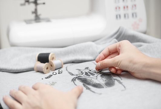 Decoration new sweatshirt. Sewing process. Women's hands behind her sewing. Sewing machine with sewing tools
