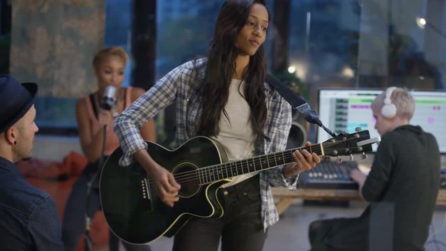  Band producing a track together in recording studio