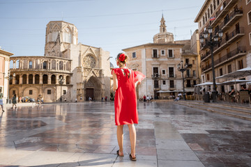 Young woman tourist in red dress standing back on the central square in Valencia city, Spain