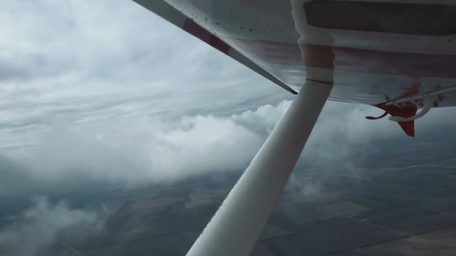 View from a small plane of grey storm clouds over an open landscape below in a concept of flying and aviation