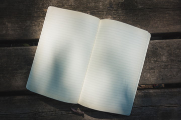 Blank empty moleskine notepad see from top on wooden table in a park
