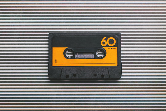 Yellow and black cassette tape on striped background.
