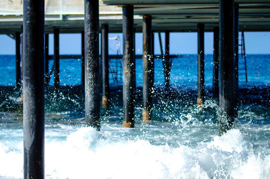 Waves break about the pier pile © Aleksey