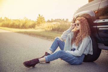 Travel. Beautiful redhair girl sitting on the road