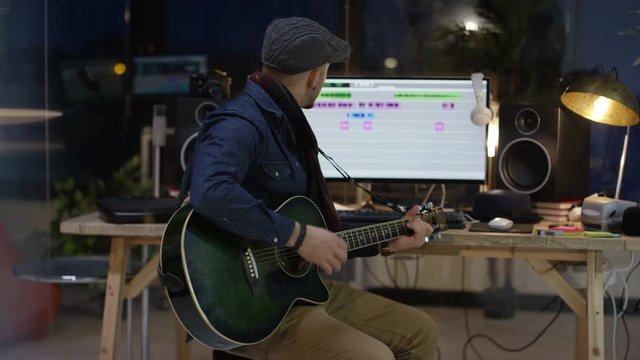  Young musician in home recording studio playing guitar & singing