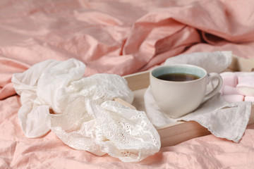 A tray with a cup of hot tea love letter and magazines in bed