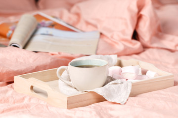 Fototapeta na wymiar A tray with a cup of hot tea love letter and magazines in bed