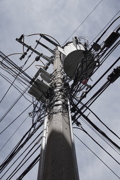 A mess of power line cables and a transformer on a pole