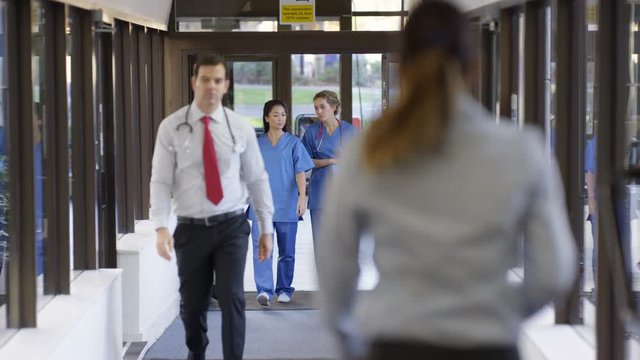  Female medical workers in discussion as they walk through hospital corridor