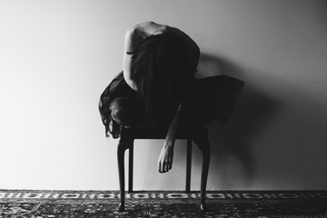 Woman wearing black tulle leaning forward in a chair with face covered