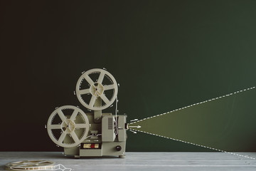 Old movie projector in front of the chalkboard with drawn light beam