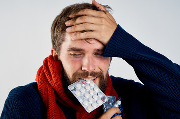 a man holds his head in the mouth of a pack of pills on a light background, naked pain, flu, ill...