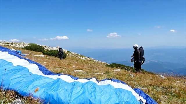 Paragliders waiting to launch from the ridge of a mountain against blue sky