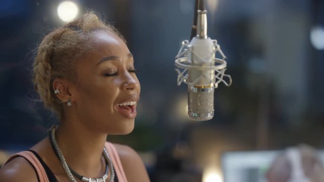  Close up female vocalist in recording studio singing into microphone