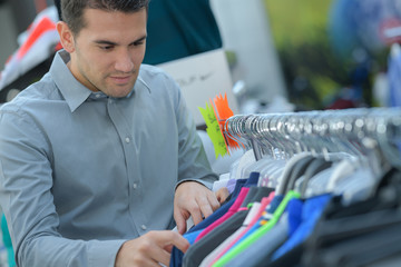 man chooses a t-shirt in the store