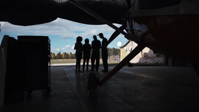 Group of people standing in hangar and looking at plane.