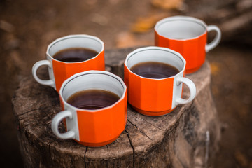 4 cups of tea in the autumn forest stand on a stump