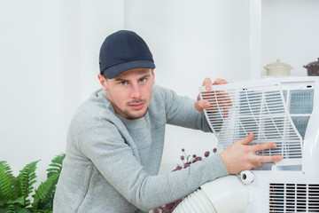 young technician installing air conditioning system indoors