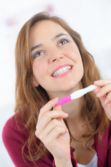 smiling woman looking on pregnant test