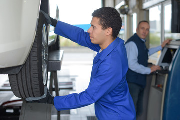 young mechanic inspecting the car wheel © auremar