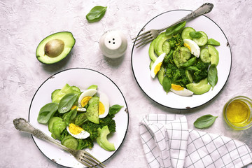 Two portions of green detox salad with avocado,broccoli,cucumber and eggs.Top view.