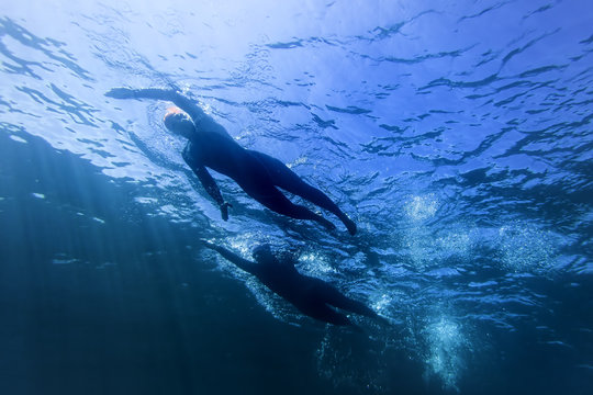 Two Female Triathlon Athletes Swimming In Race Underwater Silhouette