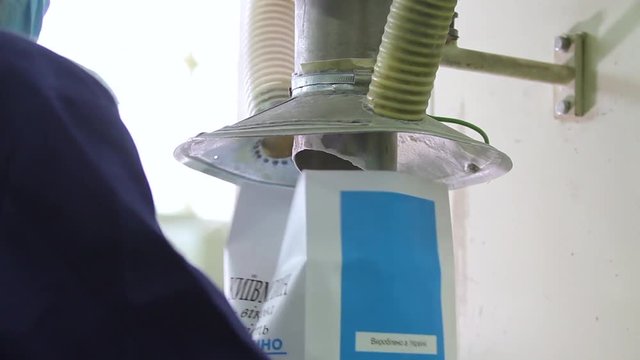 Filling empty boxes with flour at a flour mill. The conveyor for packing flour in bags. Packing flour at mill. Production line for packaging. Manufacture of food products.