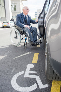 senior man in a wheelchair going in a car