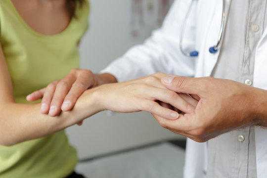 doctors hand checking female patient finger