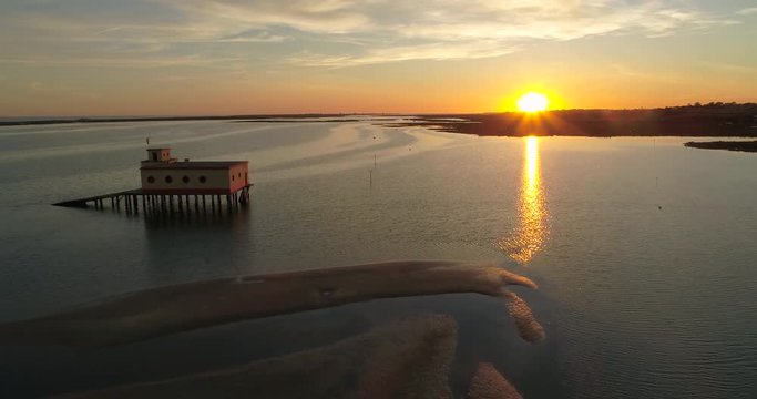 Aerial sunset and historic life-guard building at Fuseta fishing town, in Ria Formosa wetlands nature conservation park, Algarve. Portugal