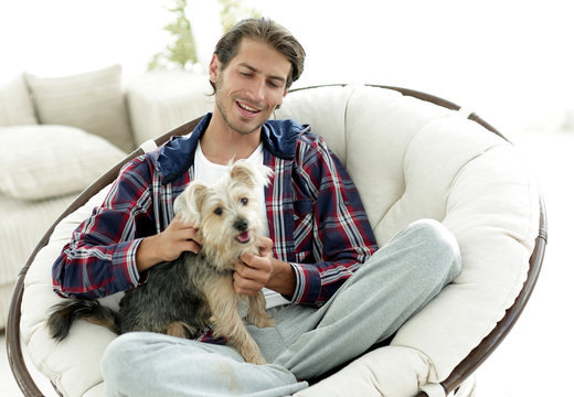handsome guy with a dog sitting in a large armchair.
