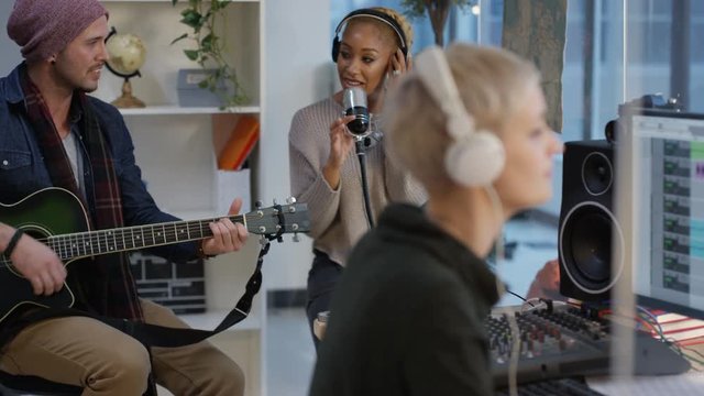  Guitarist & singer recording in the studio with technician at the mixing desk