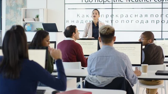 Adult students in language class with large screen showing Russian letters