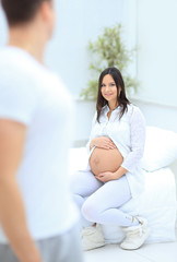 portrait of pregnant woman sitting on the couch in the new apartment.