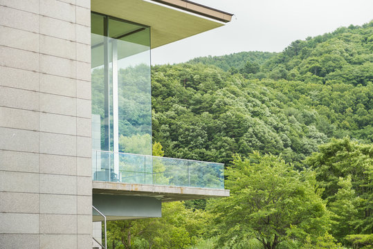 Modern glass terrace and green mountain view.