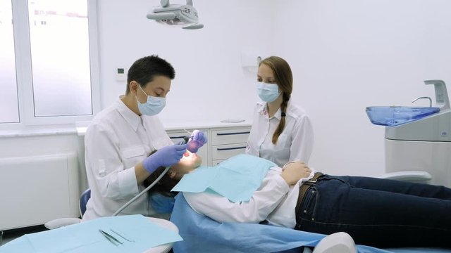 Dentist takes the drill and dental mirror for therapy procedure