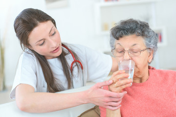 Fototapeta premium giving senior lady a glass of water