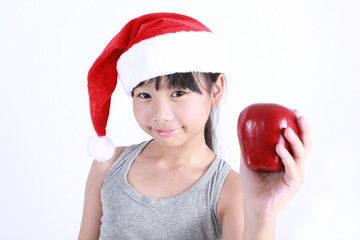 Portrait of little cute asian girl wearing red hat holding red apple