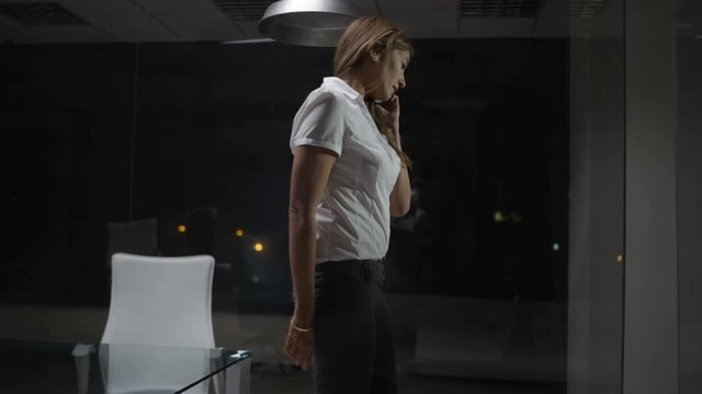  Successful city businesswoman talking on phone in her office late at night