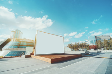 Horizontal blank information banner standing near wooden stage, empty mock-up of poster in urban settings, white clean billboard with copy space for logo, text or other advertising on bright day