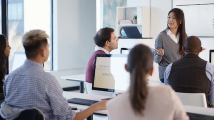  Adult students in language class with video screen showing Asian characters