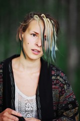 Naklejka premium Closeup portrait of cute slim brown-eyed women with colored hair strands on face street in the Park.