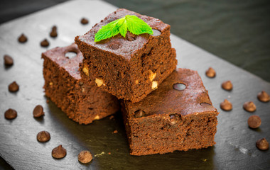 Homemade dark chocolate and cocoa brownie fudge cakes dessert with mint against black background