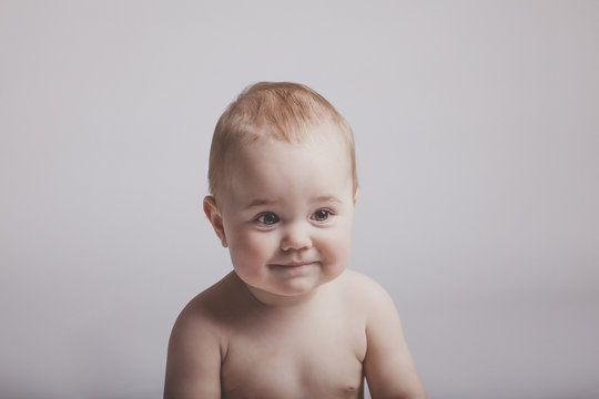 Cute baby girl with subtle smile on solid background