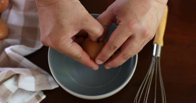 Close up chef hand braking an egg into a blue bowl then mix to prepare omelet cooking , 4k Dci resolution , top view or overhead shot